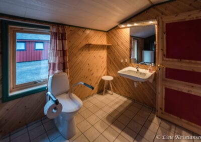 Badezimmer mit WC, Waschbecken, Spiegel und Fenster.
